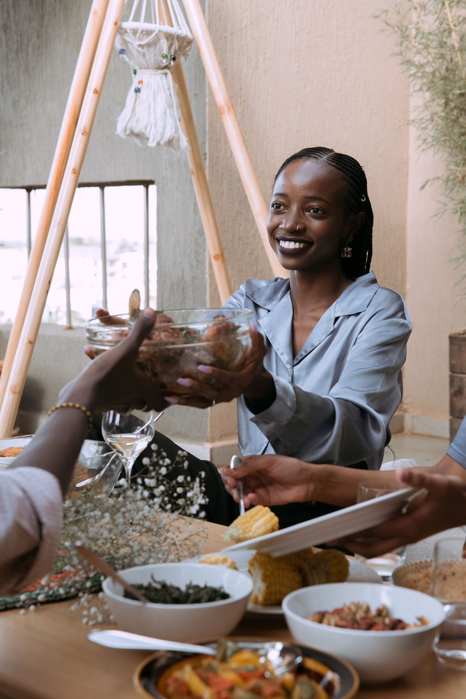 A person passes a bowl of food across a shared table during a meal.